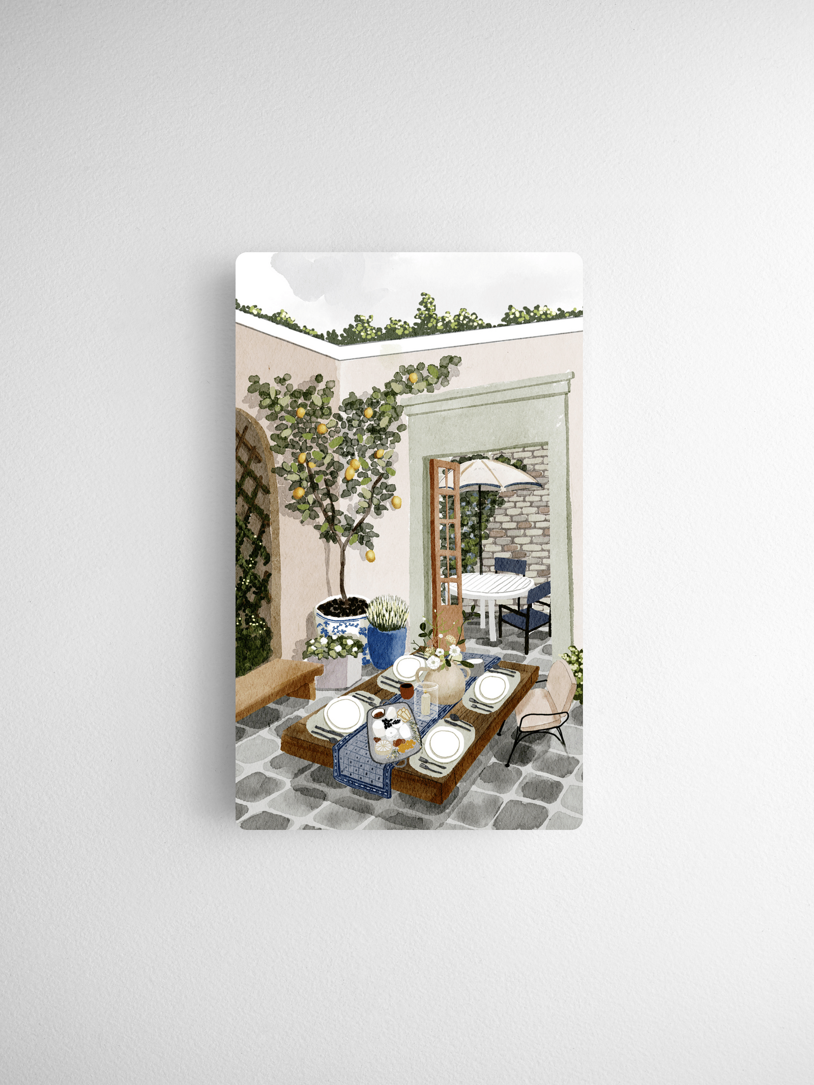 Watercolor illustration of a bright Mediterranean courtyard featuring lemon trees, rustic patio furniture, and a charming outdoor dining scene.