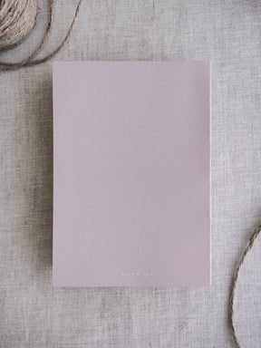 Solid, minimalist B6 grid notebook featuring a pale dusty rose cover, ideal for note-taking and journaling without page numbers.