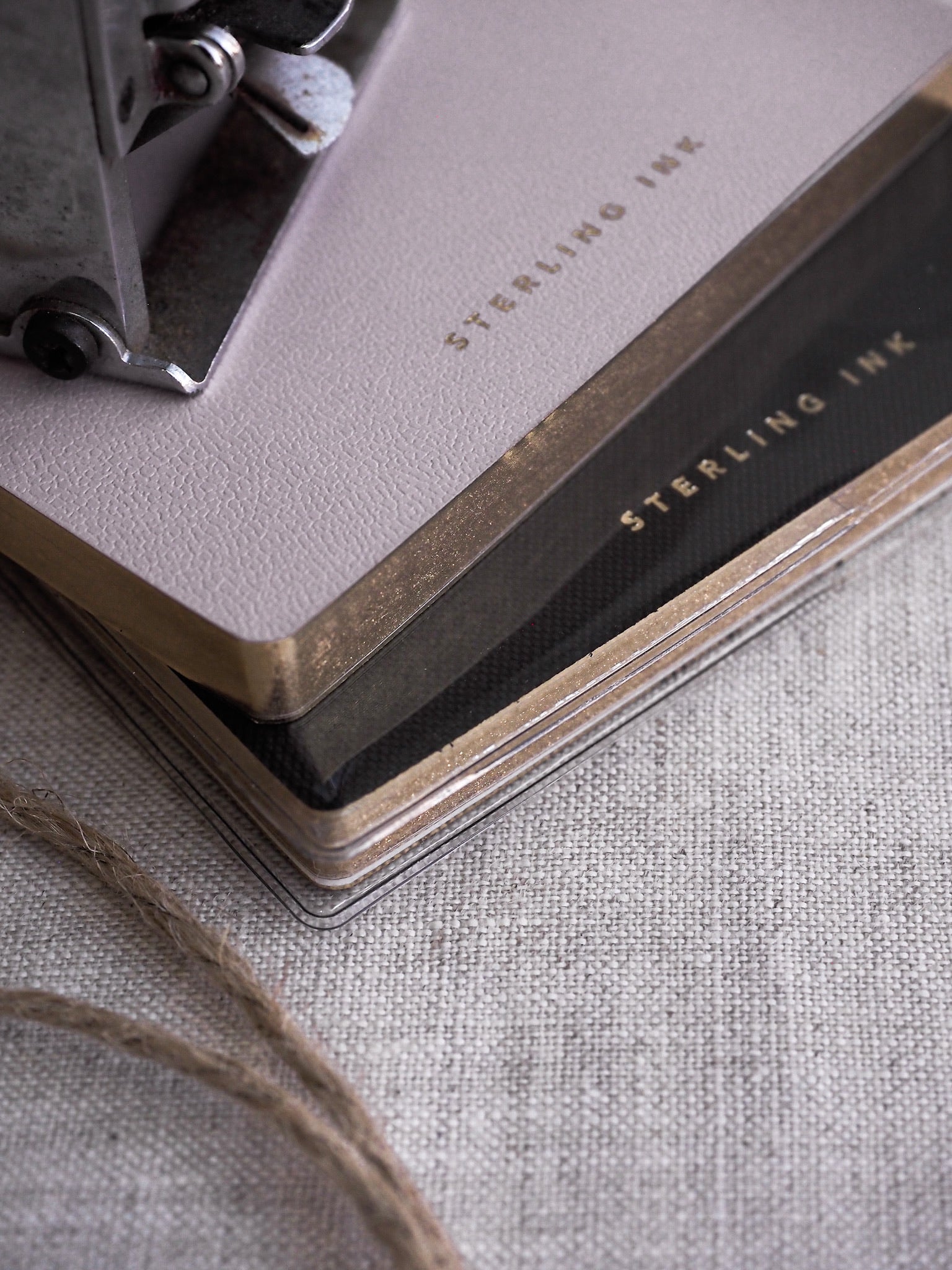 Stack of B6 grid notebooks with minimalist, solid covers in soft taupe and dark slate gray, each branded with "Sterling Ink."
