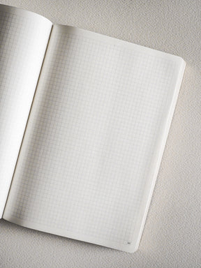 Pristine A5 notebook open to graph paper, featuring precise, light blue grid lines perfect for detailed sketching, technical drawing, or organized note-taking.