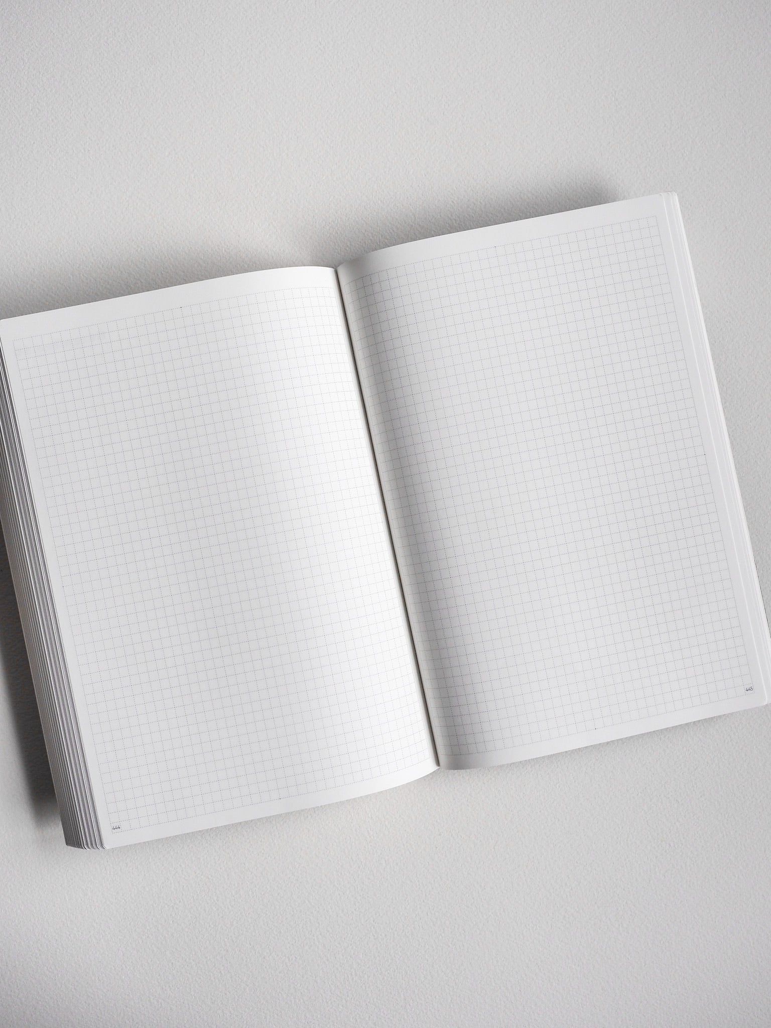 Open A5 undated daily planner featuring light, graph-style grid lines across two blank pages, ideal for journaling, note-taking, or detailed scheduling.
