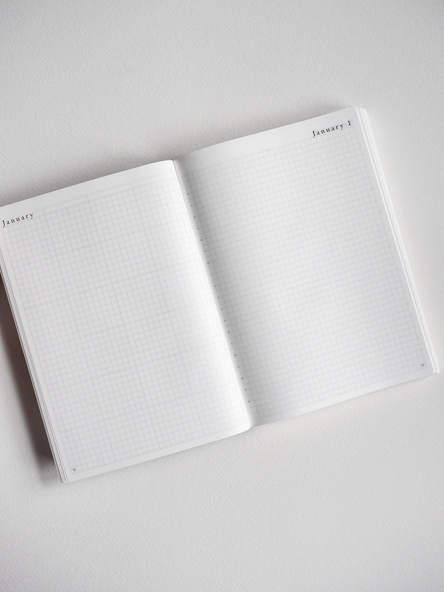 Open, undated B6 daily planner featuring white grid paper, perfect for graph note-taking, bullet journaling, and year-long organization.