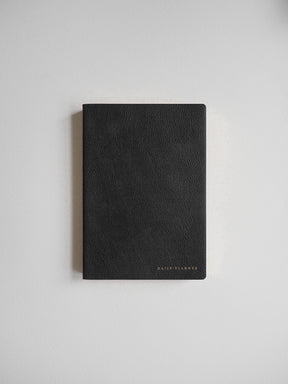 Minimalist matte black daily planner featuring a textured cover and a discreet embossed logo, perfect for writing and organization.