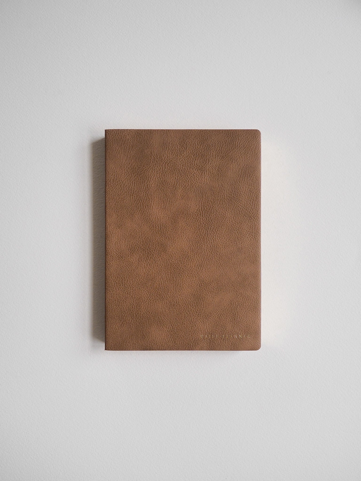 A handsome, textured cognac brown B6 undated planner, designed for comprehensive daily journaling and yearly scheduling.