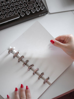 Loose leaf packet of pristine white, plain inserts bound by a continuous silver spiral coil, perfect for writing and journaling.