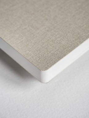 Compact vertical planner featuring a light taupe, textured linen-wrapped cover contrasted by clean white edges and spine.