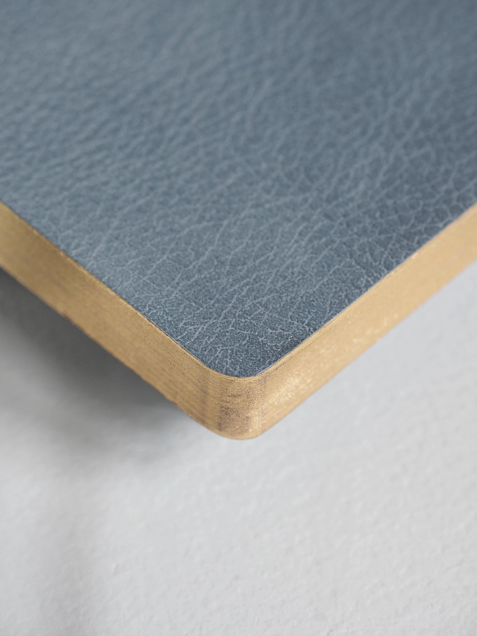 Close-up of a square product corner showing a textured slate blue top surface and a natural light wood edge, photographed on a light gray background.
#Color_Mist