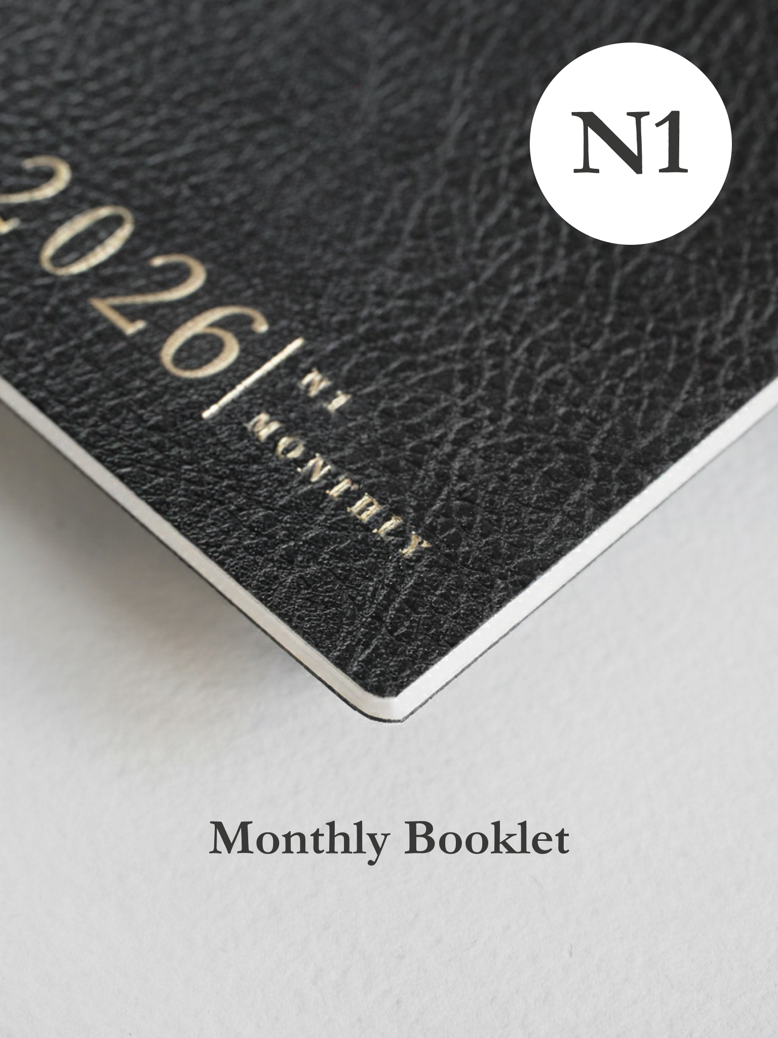 Dark gray, textured monthly booklet featuring embossed black lettering that reads "2026/N1 MONTHLY," with a prominent circular "N1" logo sticker.