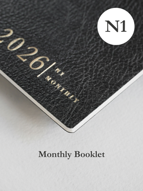 Dark gray, textured monthly booklet featuring embossed black lettering that reads "2026/N1 MONTHLY," with a prominent circular "N1" logo sticker.