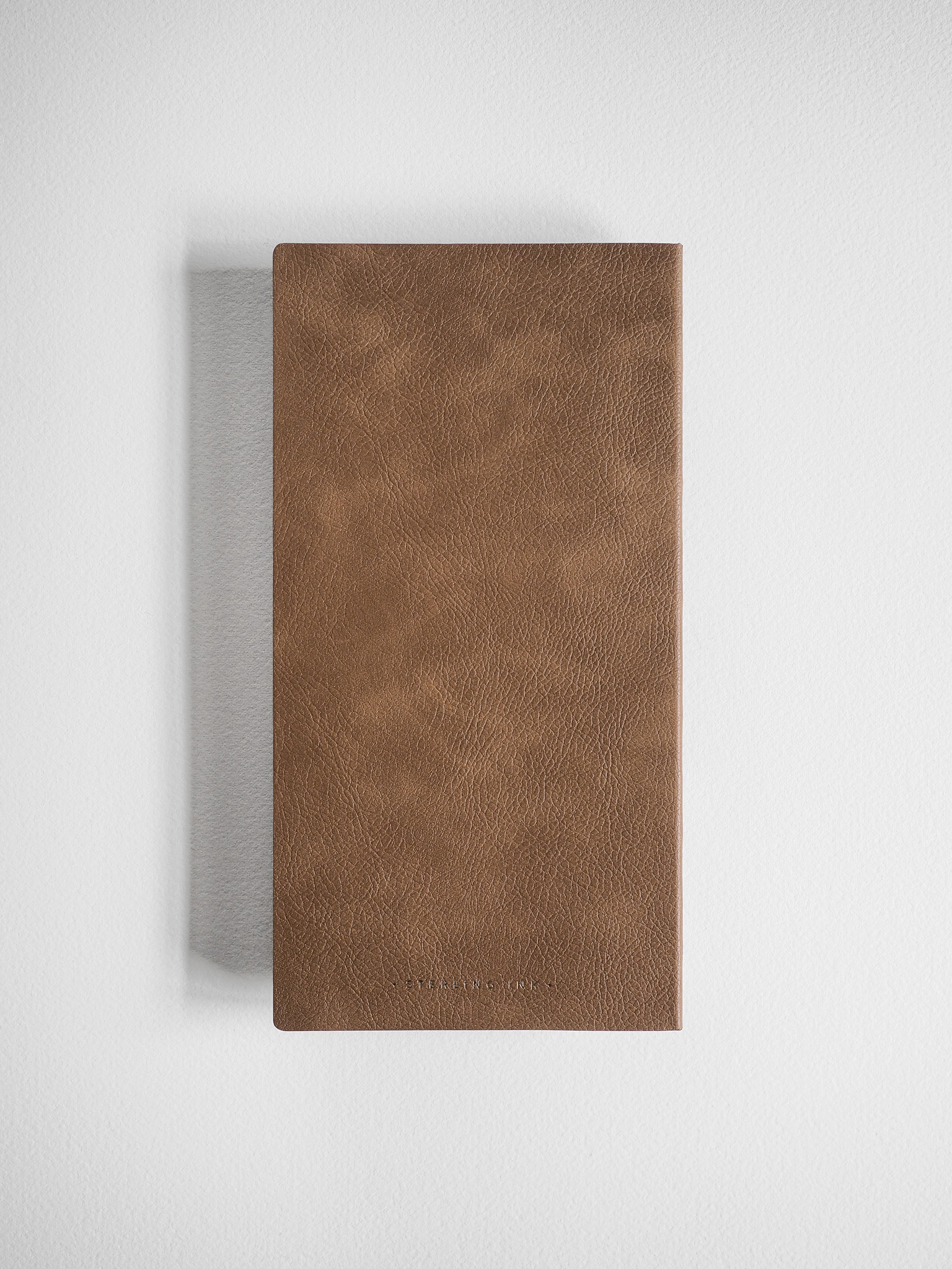 Minimalist grid notebook bound in rich, solid brown faux leather, featuring a smooth, subtly textured cover suitable for everyday writing.