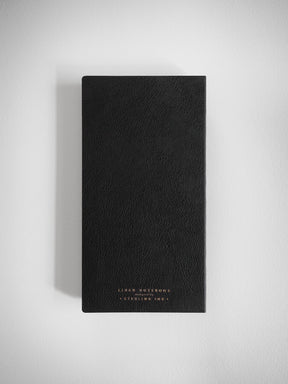 Black lined notebook featuring a textured cover and elegant gold foil stamping that identifies it as the "Lined Notebook" by "Sterling Ink."