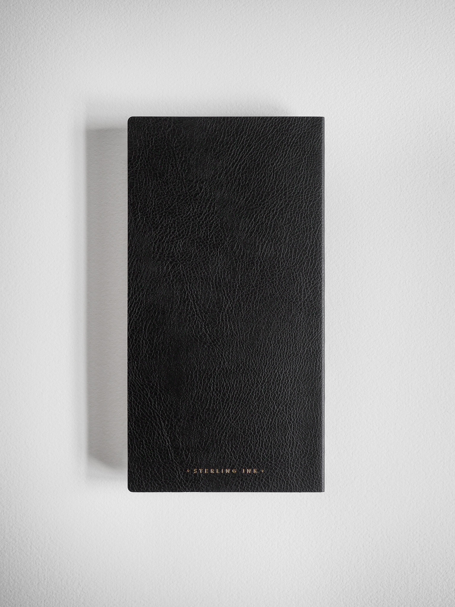 Elegant black grid notebook with a deeply textured, minimalist faux leather cover, ideal for journaling or studying.