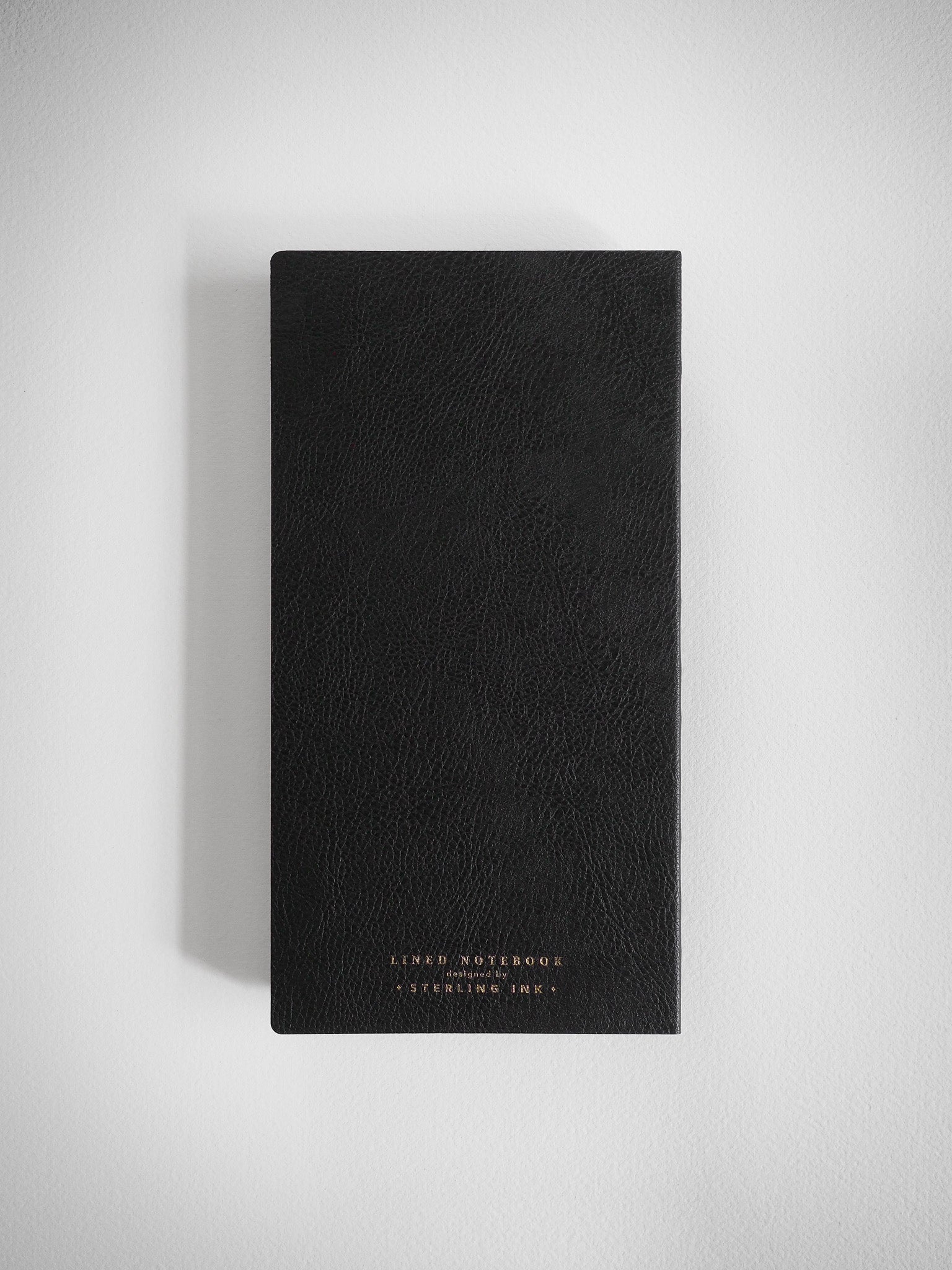 Sophisticated black lined notebook featuring a textured cover and centered gold foil stamping that reads "Lined Notebook" and "Sterling Ink."