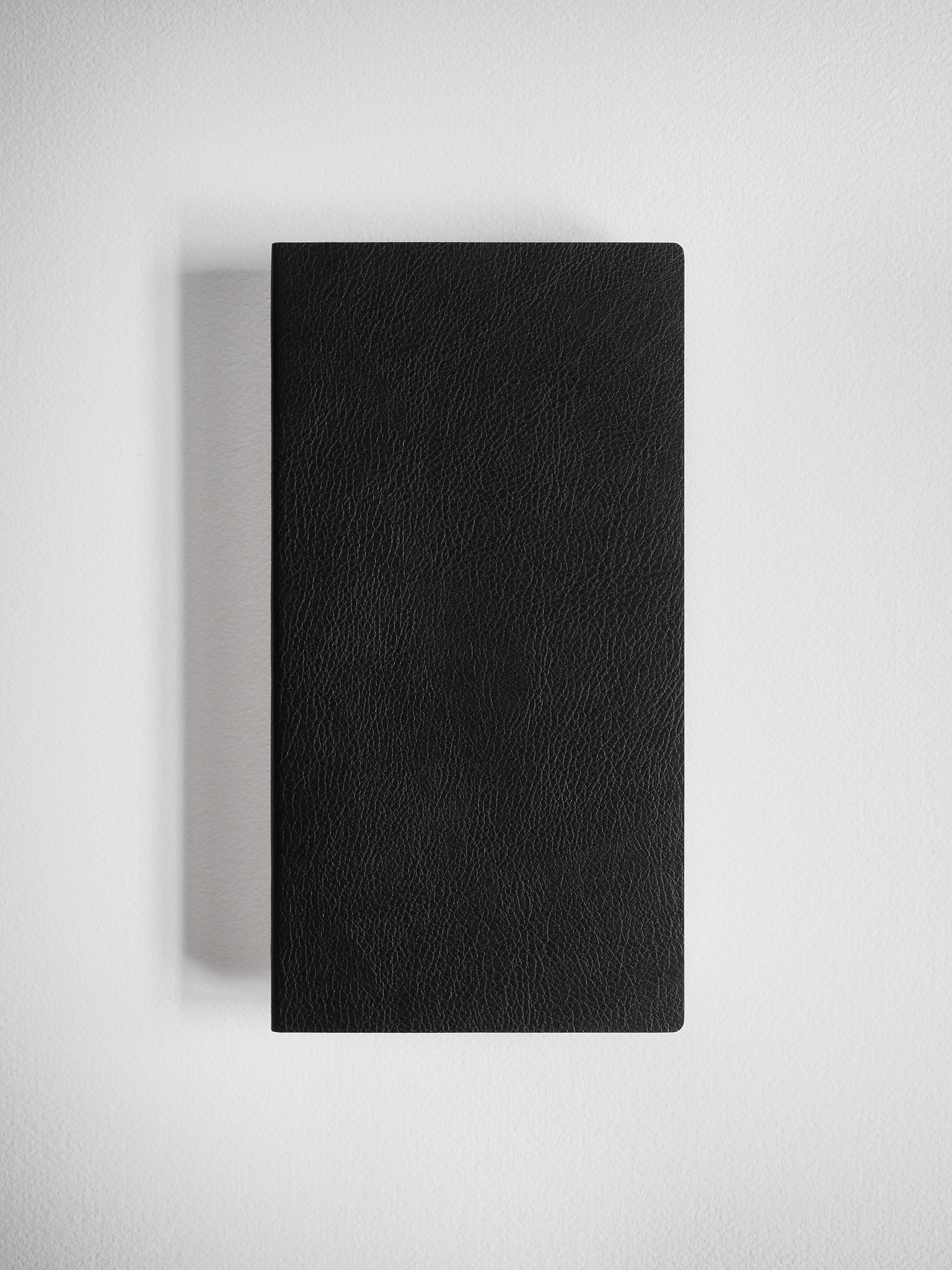 Minimalist black grid notebook featuring a sleek, solid cover with a fine, textured grain that suggests durable faux leather binding.