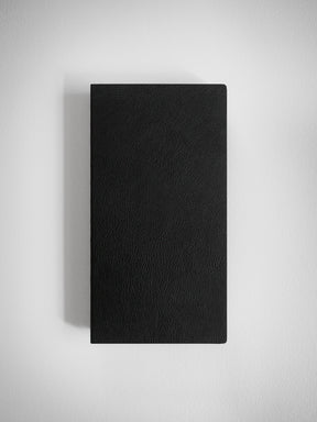 Solid black notebook with a fine, sophisticated faux leather texture, offering a minimalist writing surface perfect for notes and journaling.