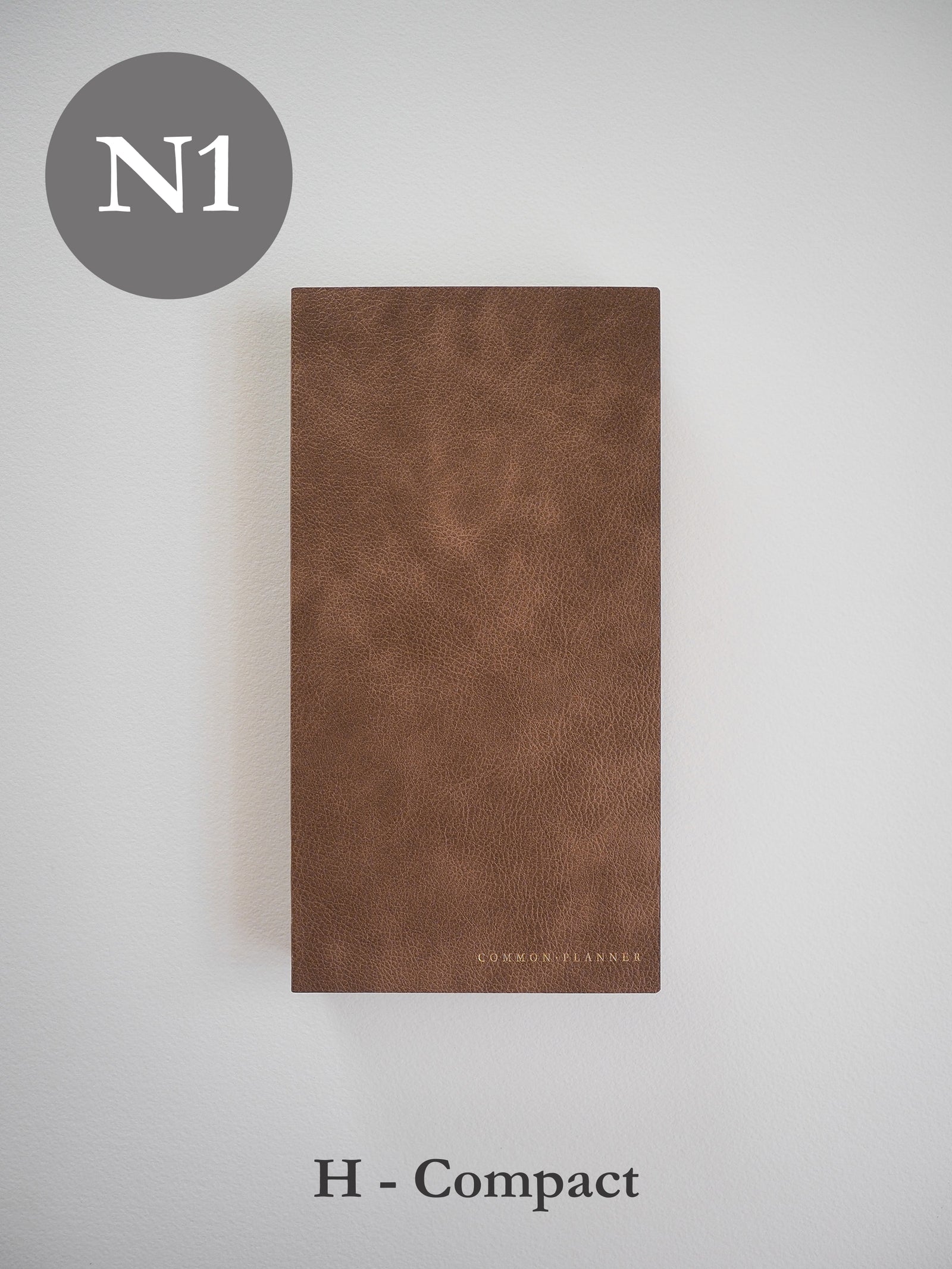 Minimalist brown faux leather planner cover, featuring a structured, compact design with the "COMMON PLANNER" logo subtly embossed near the bottom edge.