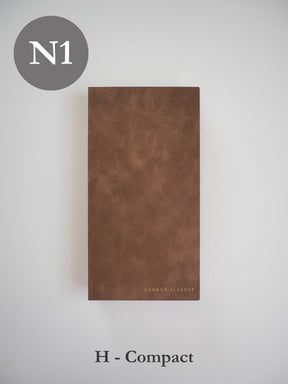 Minimalist brown faux leather planner cover, featuring a structured, compact design with the "COMMON PLANNER" logo subtly embossed near the bottom edge.