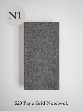 Dark charcoal notebook featuring a subtly woven texture and solid cover, designed for general notes, sketching, or grid work.