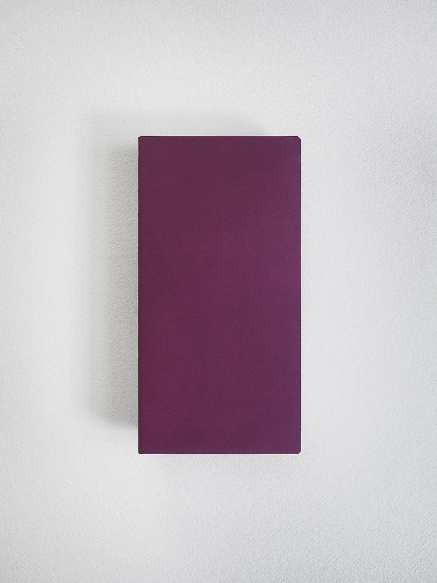 A solid, deep plum-colored notebook with a plain, minimalist cover, featuring a uniform, rich magenta hue.
