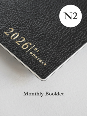 Dark, textured monthly planner booklet displaying "2026/ N2 MONTHLY" in elegant gold lettering.