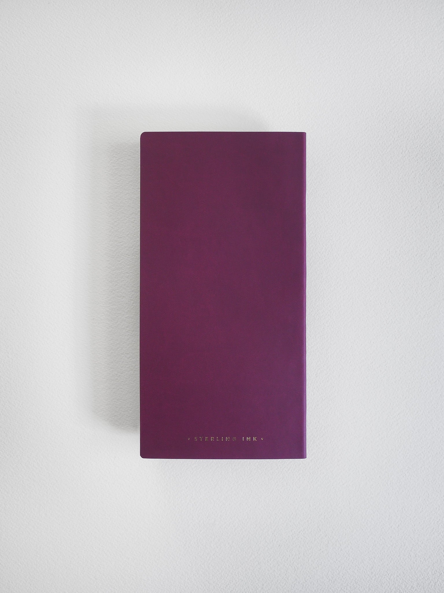 A solid plum-colored notebook featuring a smooth, minimalist cover and centered branding, perfect for journaling and note-taking.
