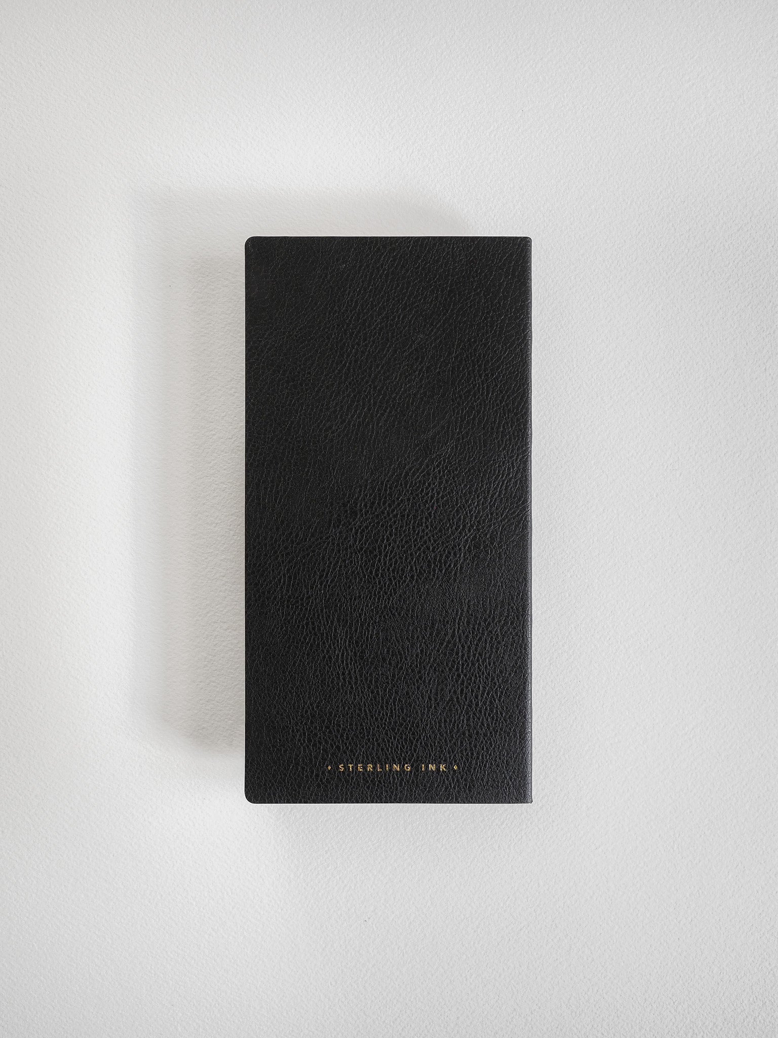 Matte black grid notebook with a textured, faux leather cover, featuring subtle, elegant branding for a sophisticated writing journal.