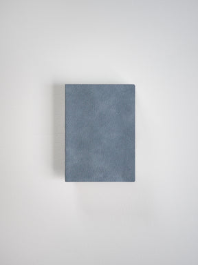 A rectangular notebook featuring a smooth, muted slate blue, matte faux leather cover.
