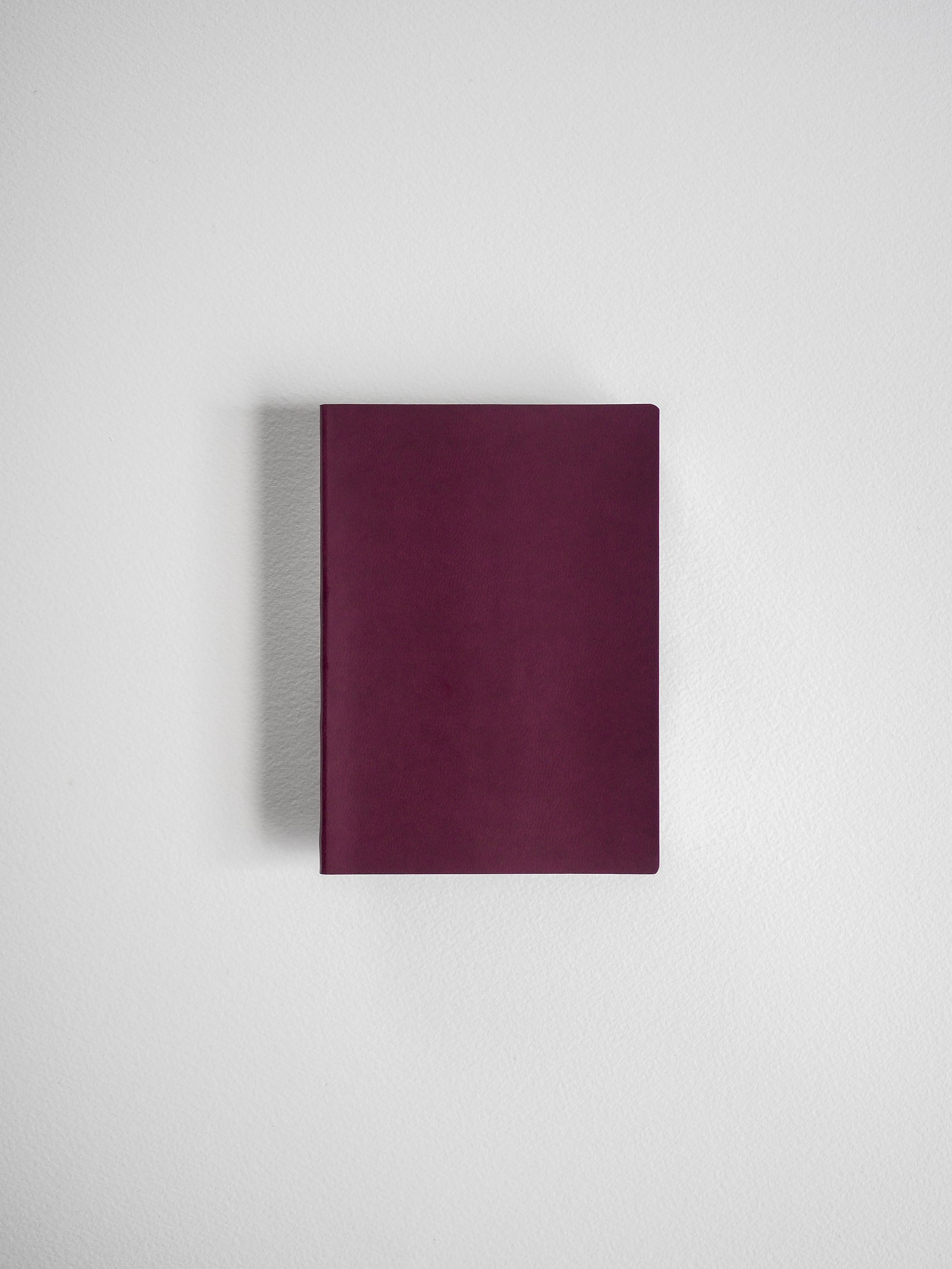 Minimalist deep burgundy notebook with a smooth, solid cover, ideal for grid note-taking, journaling, or travel documentation.