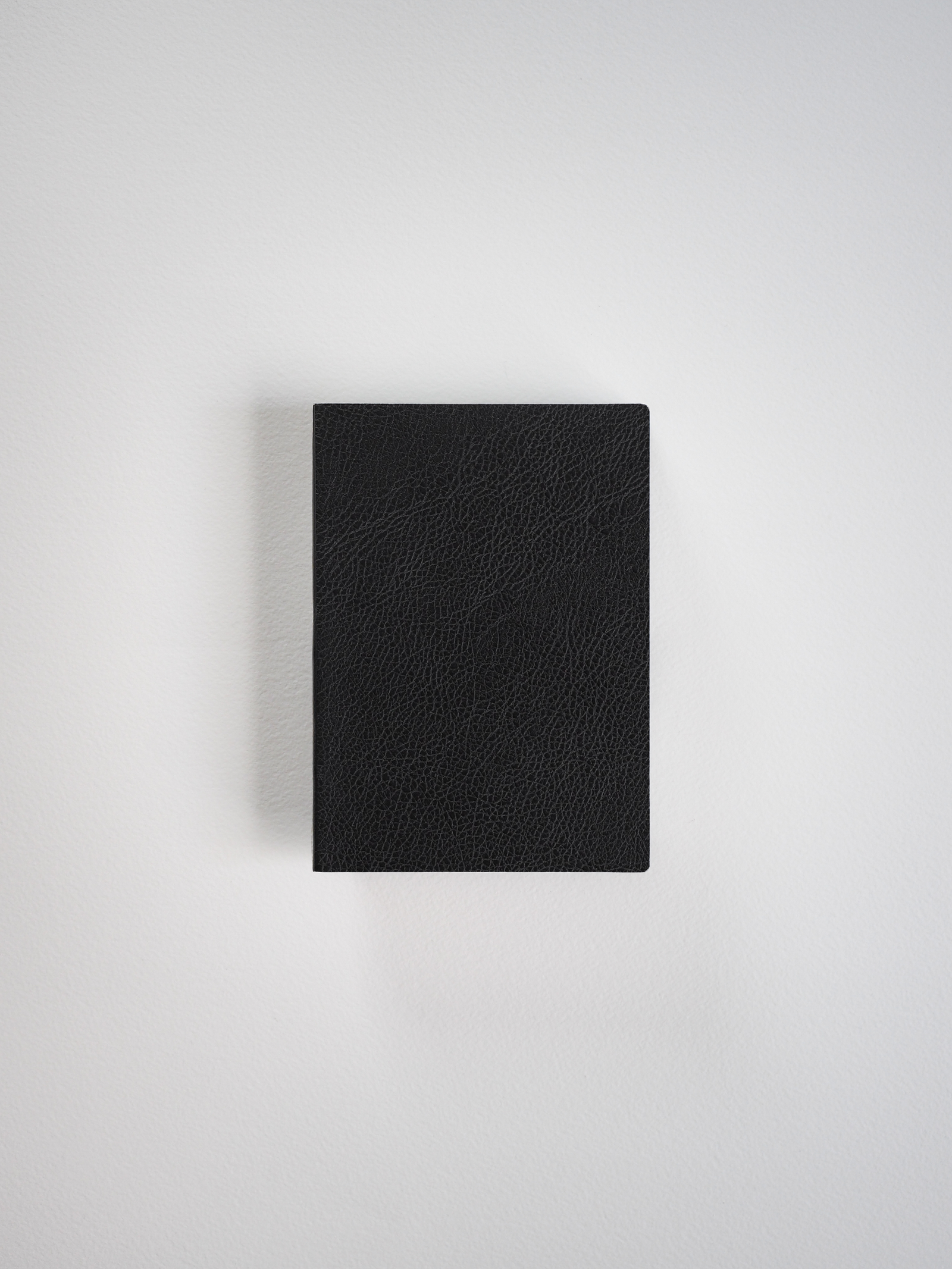 Solid black, textured faux leather journal or notebook cover, featuring a sophisticated, uniform rectangular design ideal for writing and journaling.