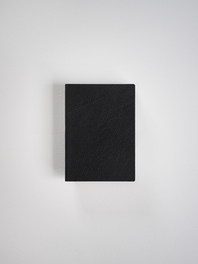 Solid black, textured faux leather journal or notebook cover, featuring a sophisticated, uniform rectangular design ideal for writing and journaling.