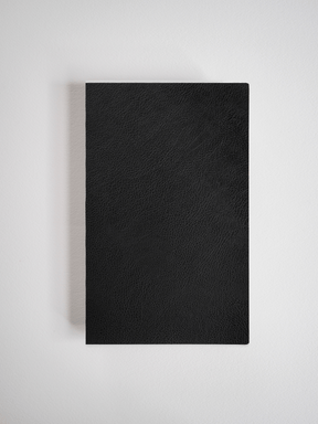Minimalist A5 slim notebook featuring a deep black, textured faux-leather cover, ideal for journaling or professional use.