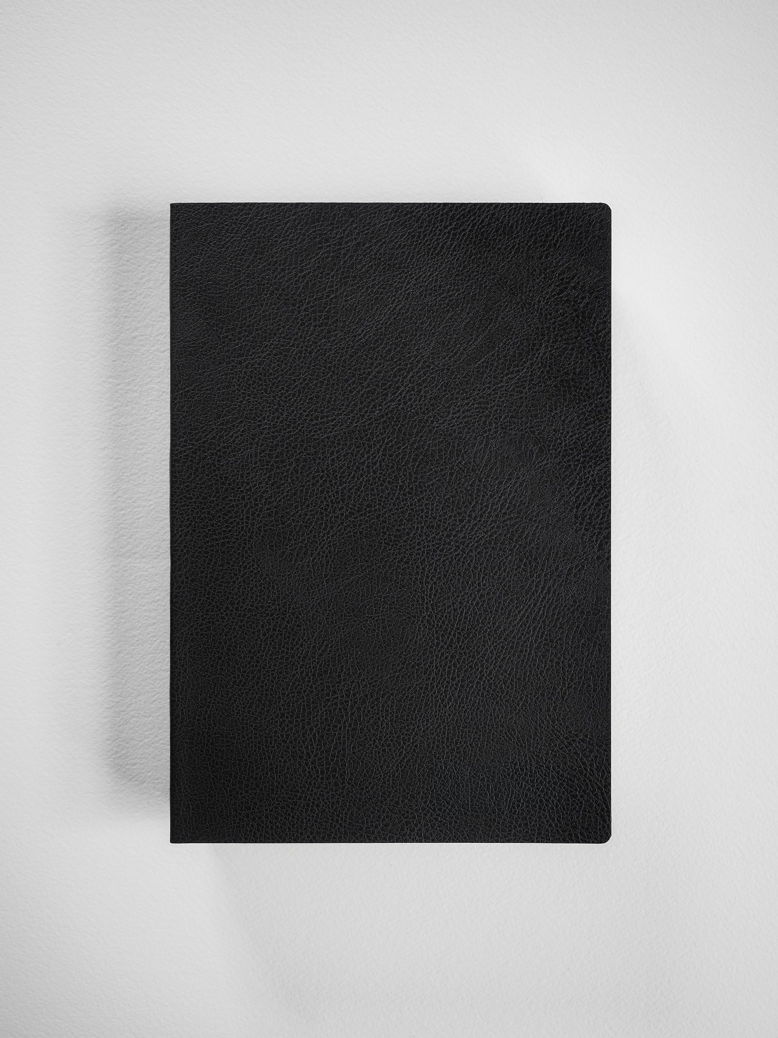 Sleek black A5 grid notebook featuring a smooth, matte, textured faux-leather cover, ideal for journaling or academic planning.