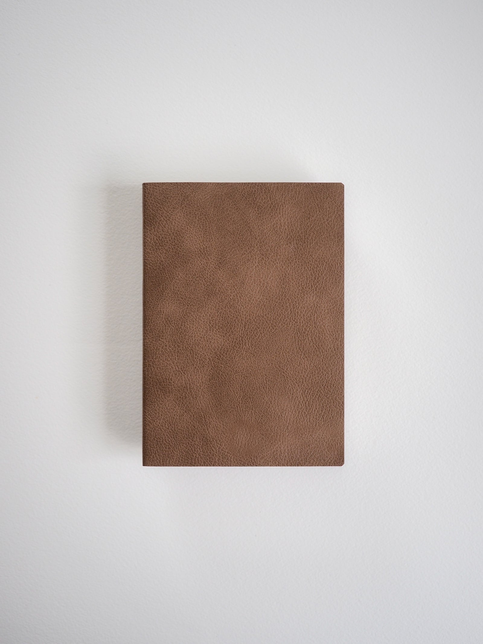 Solid, rectangular A6 notebook with a smooth, matte brown faux leather cover, designed for journaling or academic grids.