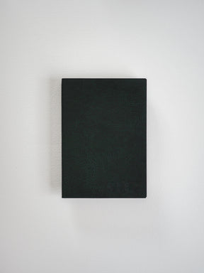 Matte black A6 grid notebook featuring a textured, dark faux-leather cover, ideal for detailed journaling, planning, or structured writing.