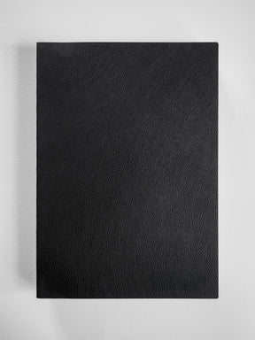 Deep matte black notebook cover featuring a finely textured, professional faux leather finish suitable for comprehensive grid planning.
