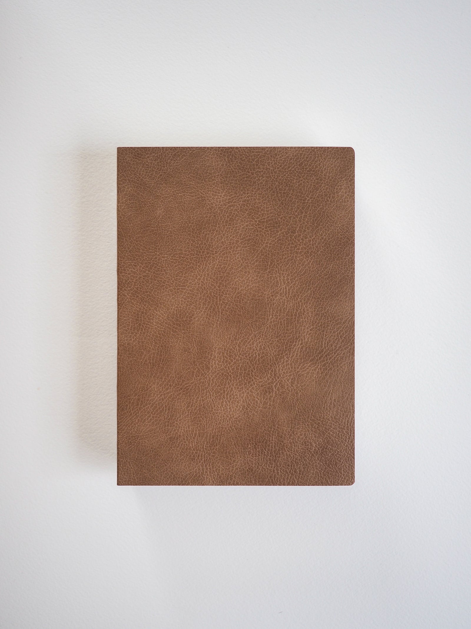 A solid, minimalist notebook featuring a rich, matte tan faux leather cover, designed for B6 sizing and comprehensive writing or planning.