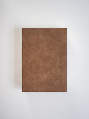A solid, minimalist notebook featuring a rich, matte tan faux leather cover, designed for B6 sizing and comprehensive writing or planning.