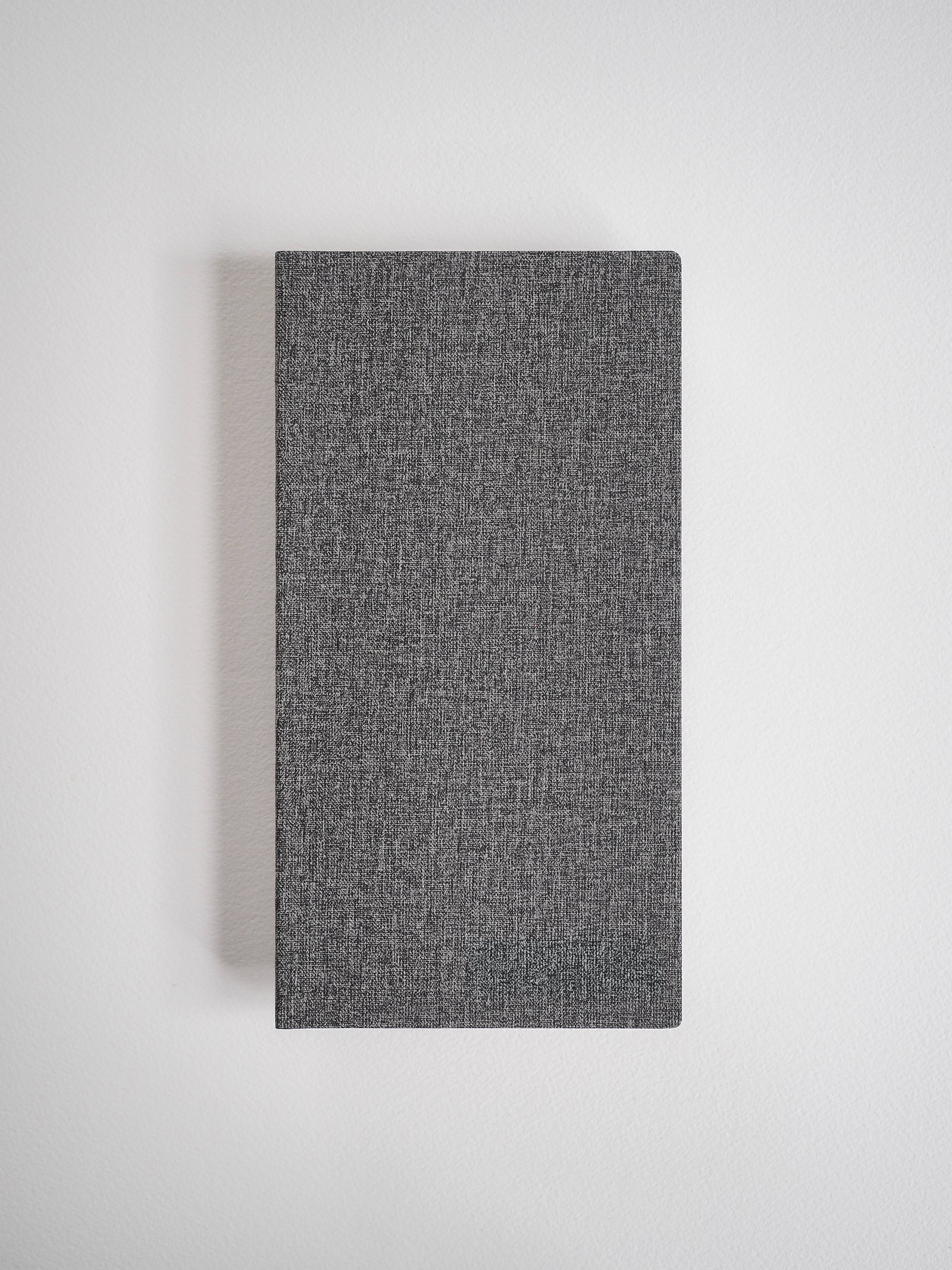 Textured charcoal gray grid notebook with a minimalist, woven cover, suitable for journaling and planning.