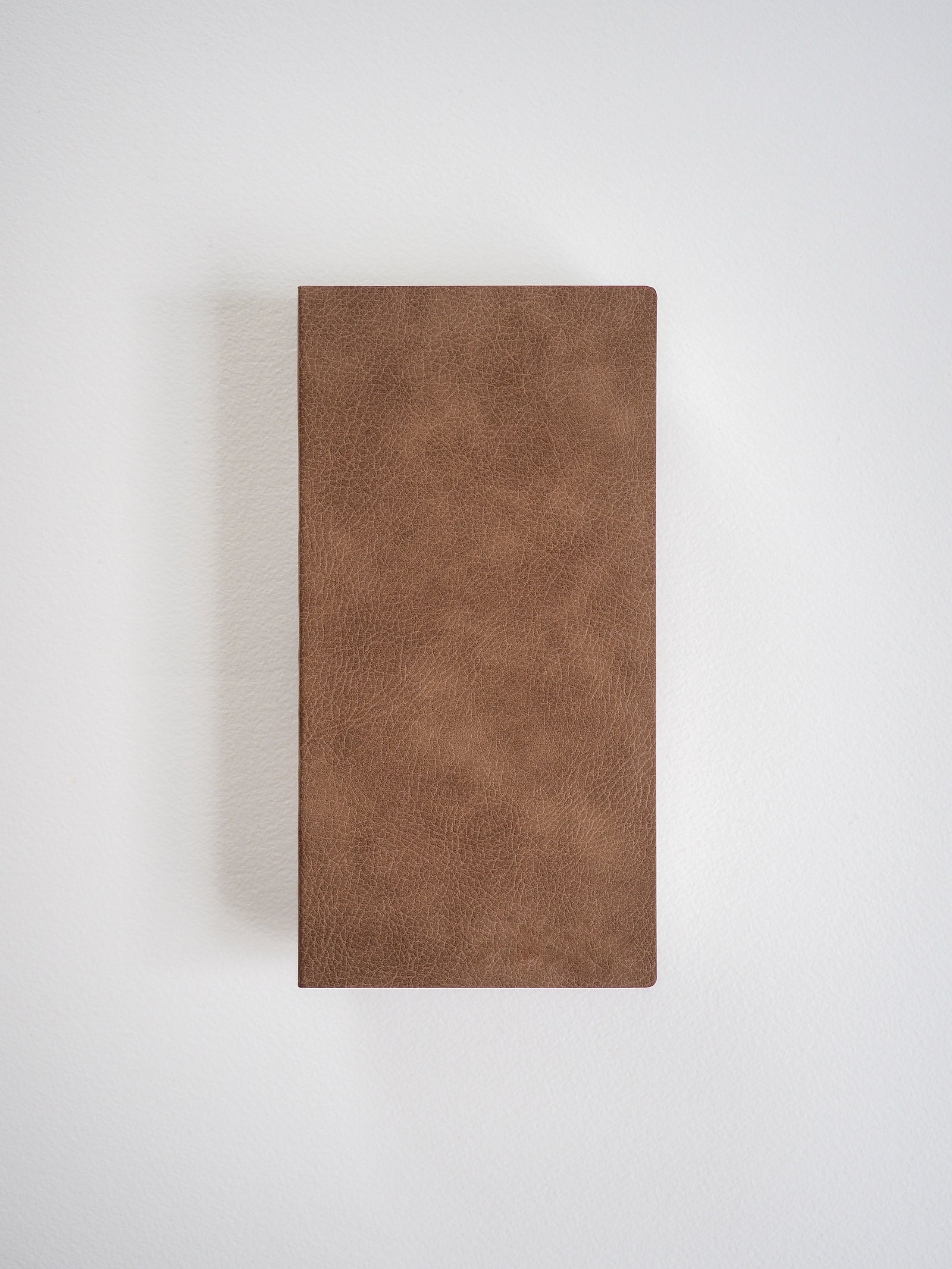 Solid, rectangular grid notebook bound with a rich, uniform brown cover that features a subtly textured, faux leather finish.