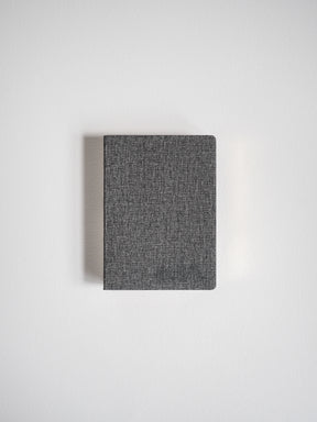 Portable grid notebook featuring a dark, heathered charcoal grey textured cover for everyday writing.