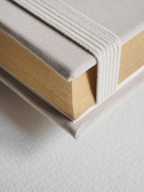 Textured, A5 hardcover diary in a muted beige tone, featuring a durable binding and visible edges of cream-colored inner pages.