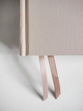 Natural linen-textured hardcover diary with a light beige finish and attached pale ribbon bookmarks, perfect for an undated five-year record.