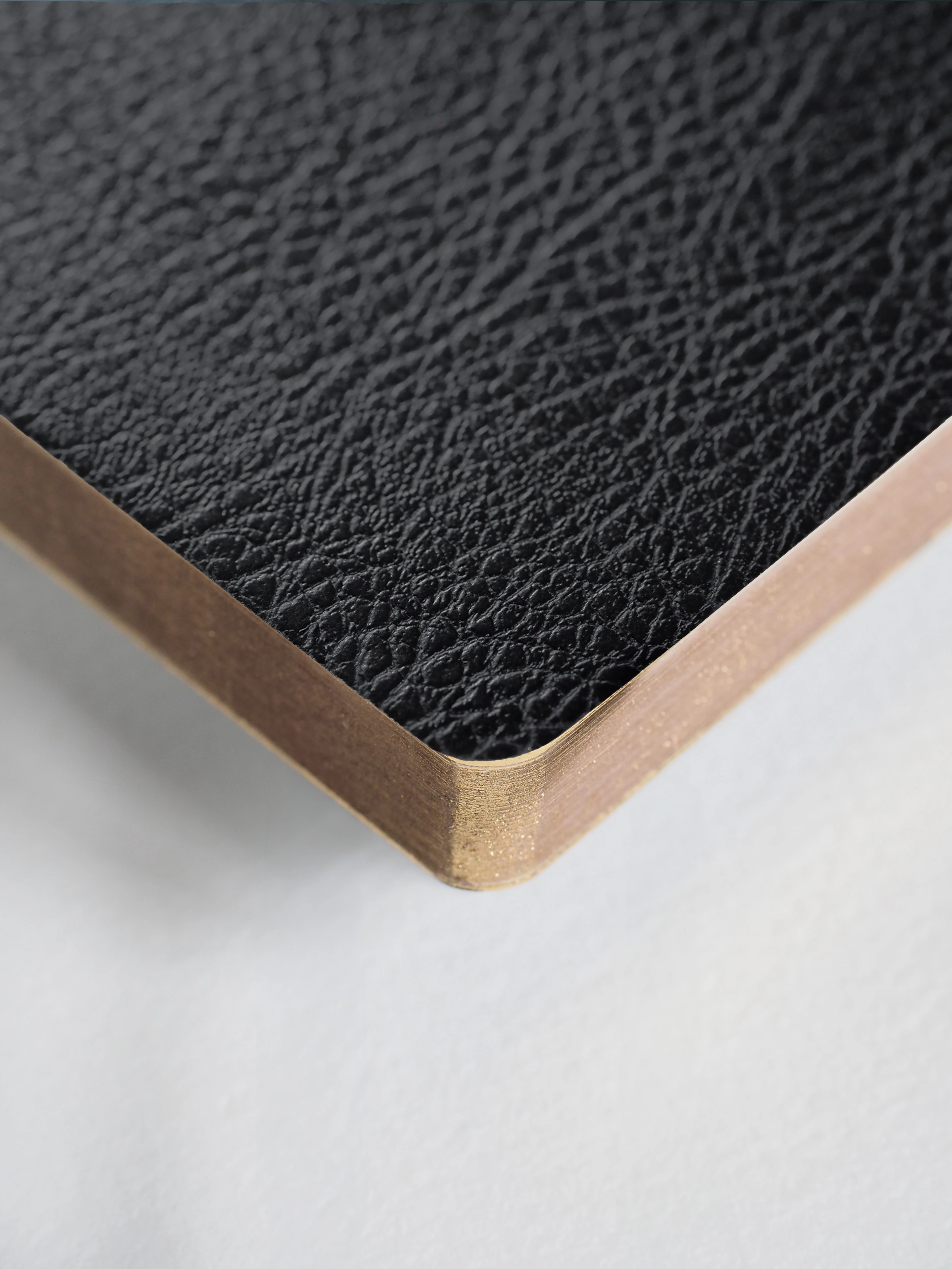 Close-up of a textured black surface with a wooden border on a white background
#Color_Onyx