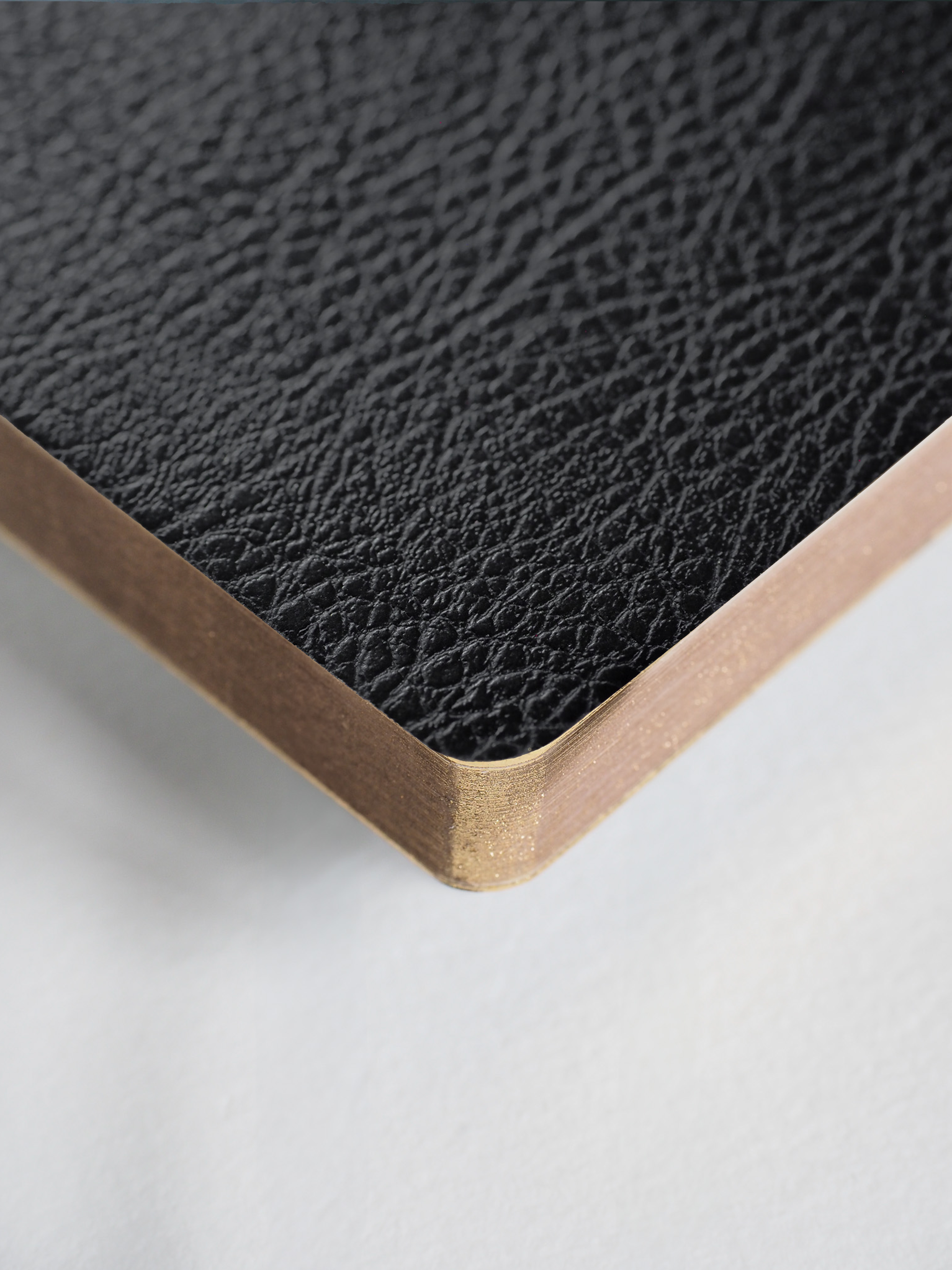 Black textured faux leather planner with a striking metallic gold binding edge, designed as a compact, undated journal.