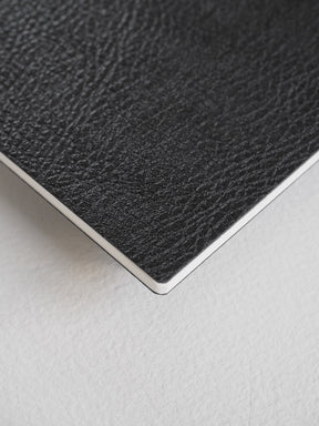Stylish black passport notebook with a fine-grained, textured faux-leather cover perfect for journaling and writing notes.