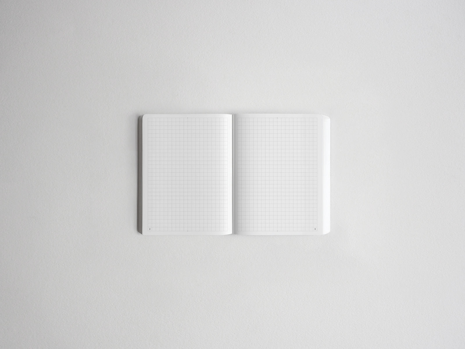 An open white notebook with light gray grid paper pages, centered on a clean white background.