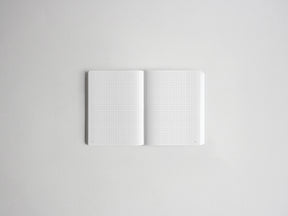 An open white notebook with light gray grid paper pages, centered on a clean white background.
