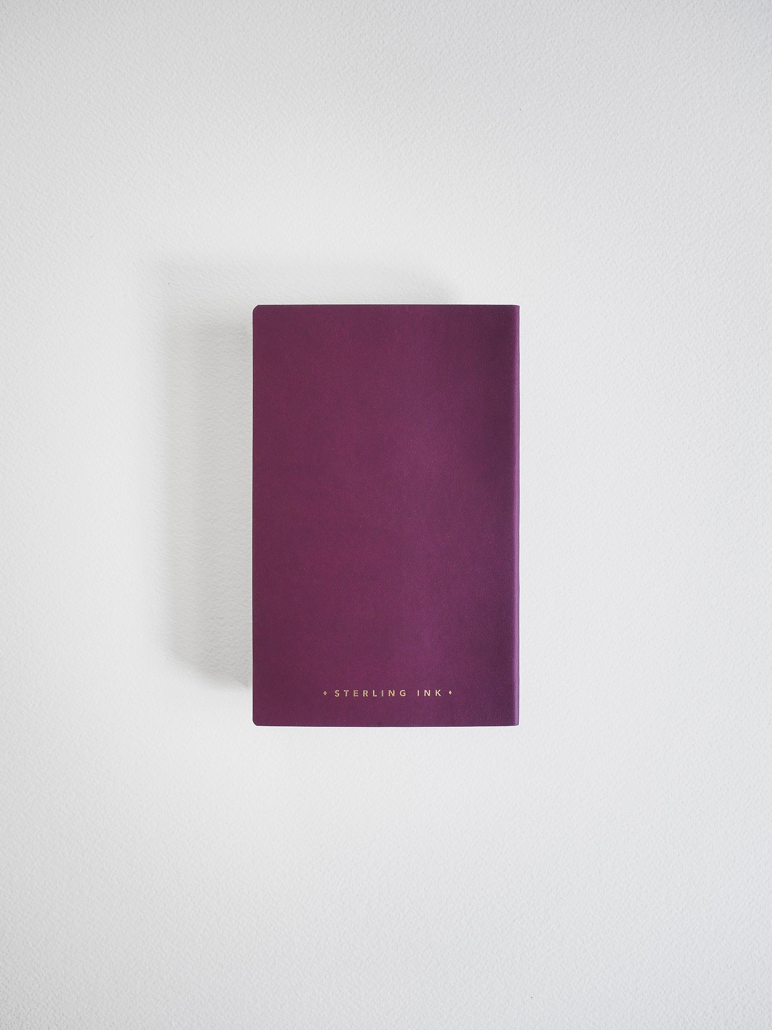 Deep plum pocket notebook featuring a solid matte cover and centered "STERLING INK" branding.