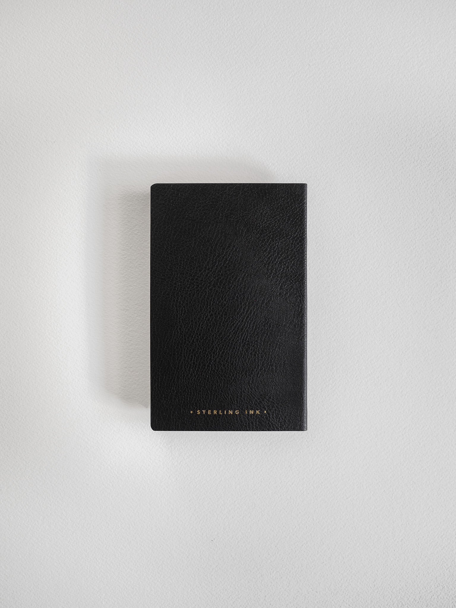 Matte black pocket notebook featuring a minimalist design and subtle gold-stamped "Sterling Ink" lettering on the cover.