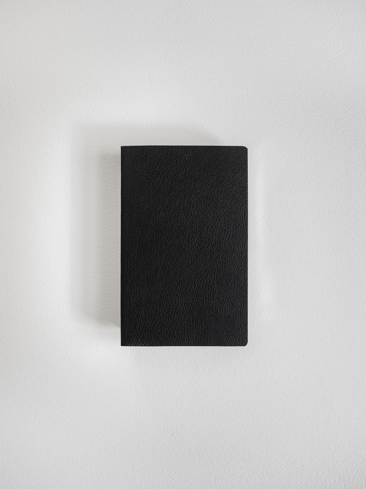 Minimalist pocket notebook featuring a deep black, smooth matte cover, perfect for versatile writing and on-the-go journaling.